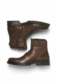 Botas de tobillo de cuero marrón con cordones en el frente, cremallera lateral y acentos texturizados. Suela de goma negra resistente con relieve.