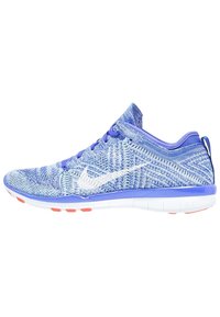 Zapatilla deportiva de punto azul con logo de swoosh blanco, parte superior texturizada, cuello acolchado y suela blanca con acentos naranjas.