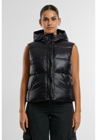 Gilet en doudoune noir avec capuche, à finition brillante, boutons-pression, poches latérales et design court. Motif matelassé texturé.