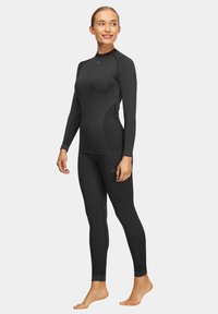 Czarny zestaw termicznej odzieży aktywnej, składający się z długiego rękawa topu z wysokim kołnierzem oraz dopasowanych legginsów, wykonany z rozciągliwego, oddychającego materiału.