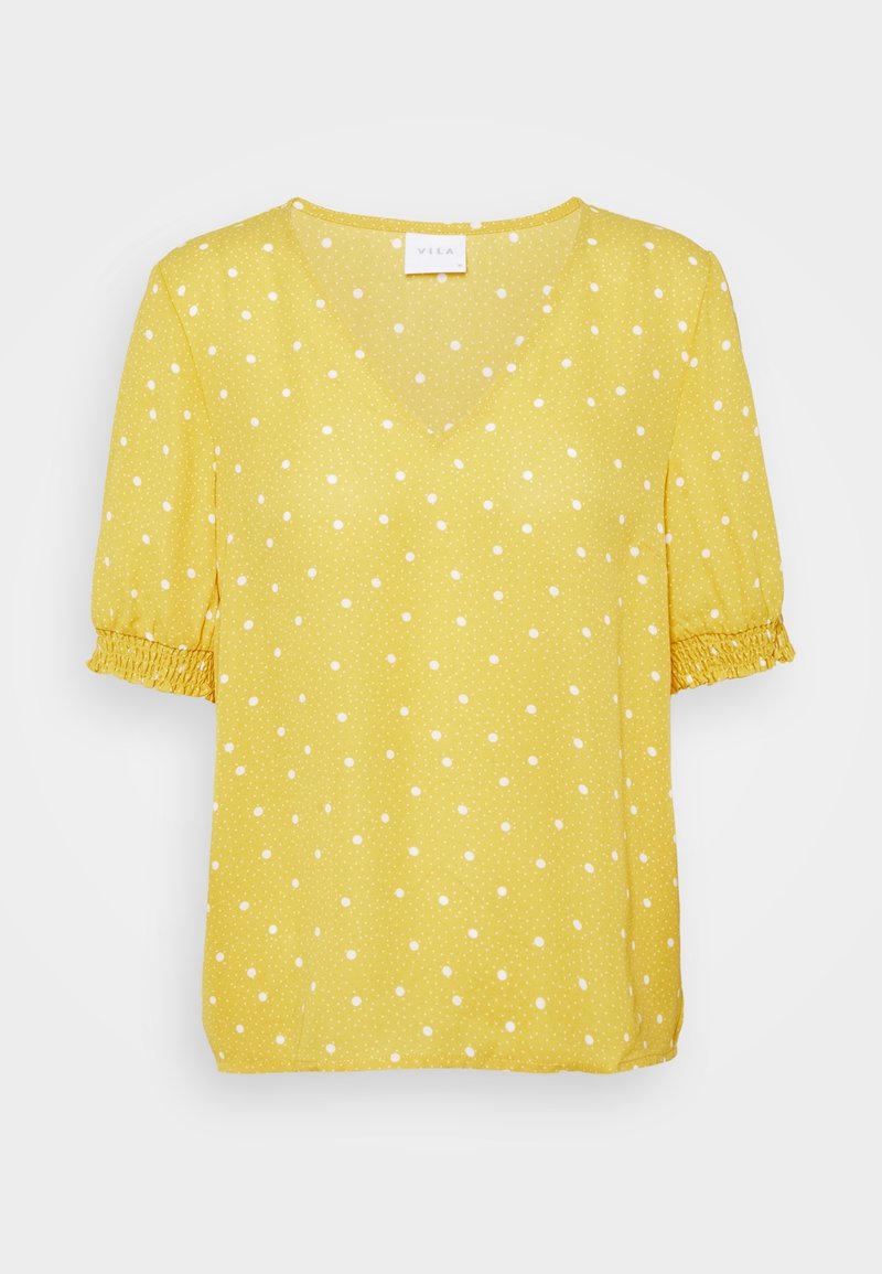 Blouse jaune à manches courtes avec pois blancs, col en V et poignets smockés élastiques aux manches.