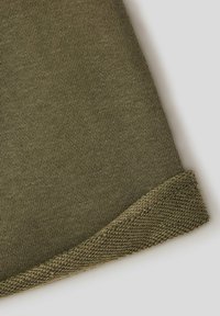 Tessuto di cotone verde oliva con una trama liscia e un motivo di maglia visibile. Il bordo presenta un orlo ripiegato con un dettaglio di cucitura a contrasto.