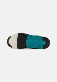 Suela de zapato deportivo con un diseño segmentado que incluye secciones en negro, blanco y verde azulado; goma texturizada para mayor agarre y durabilidad.