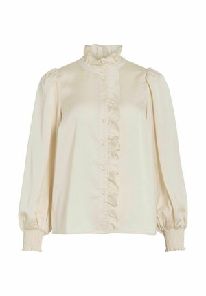 Krémová blůza s volánkovým předním dílem, vysokým límcem a nadýchanými rukávy. Vyrobena z hladké tkaniny, má knoflíkové zapínání a nařasené manžety.