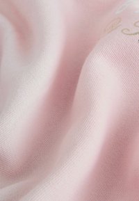 Tela rosa claro con una textura suave, que presenta sutiles variaciones en el color y texto integrado en colores contrastantes.