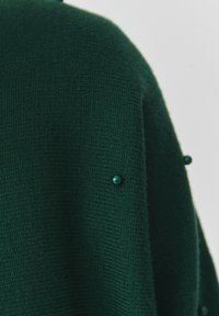 Maglione verde lavorato a maglia con un tessuto testurizzato, accenti in teal tondi e una vestibilità rilassata con minimalismi sulle spalle.