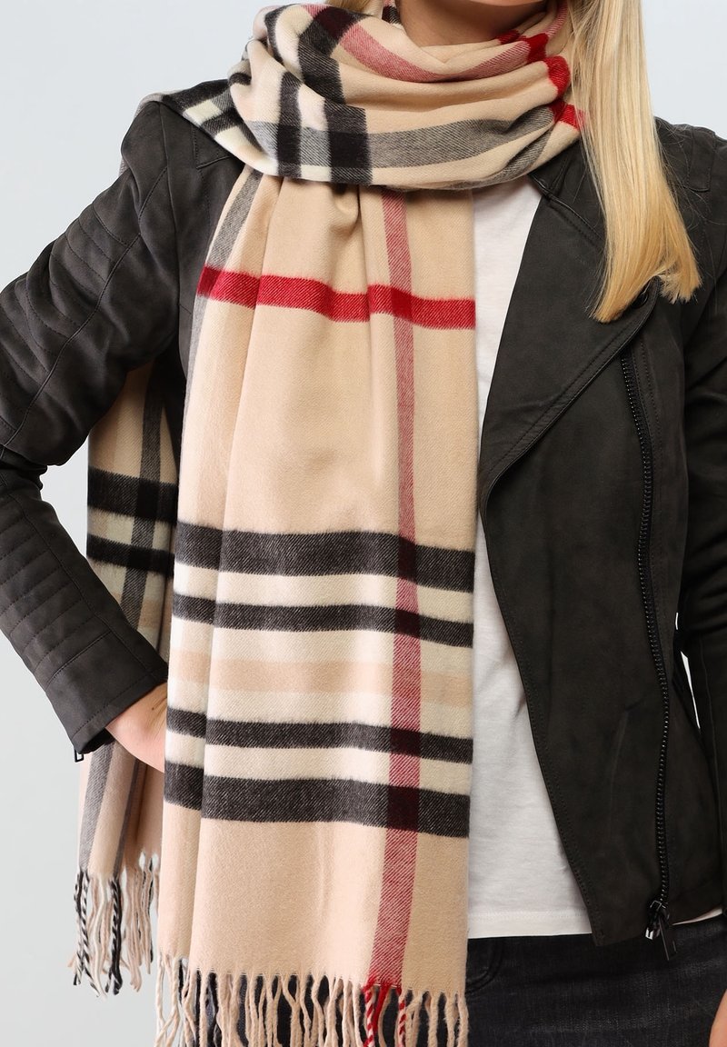 Écharpe à carreaux beige avec des rayures noires, rouges et blanches, en tissu doux. Présente des bords frangés et se drape lâchement autour du cou.