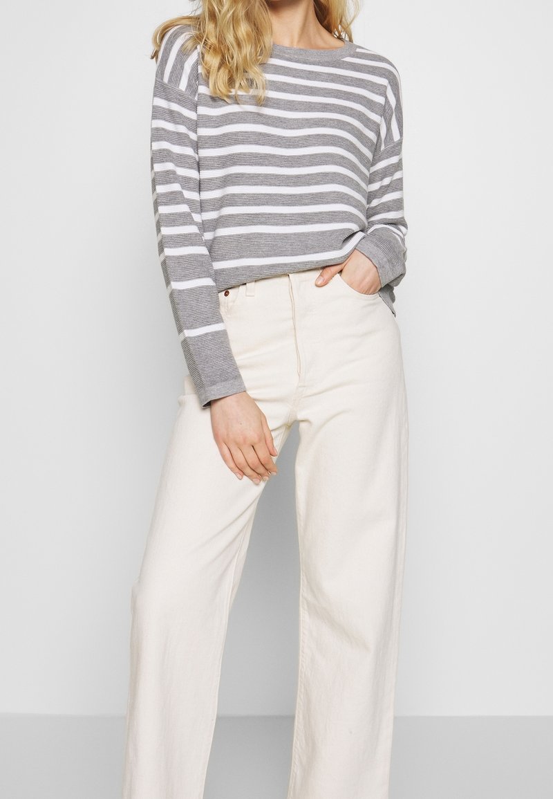 Grijs en witte gestreepte lange mouwen top, relaxte pasvorm, gecombineerd met hooggetailleerde crèmekleurige wijde broek, minimalistisch ontwerp, zachte textuur.