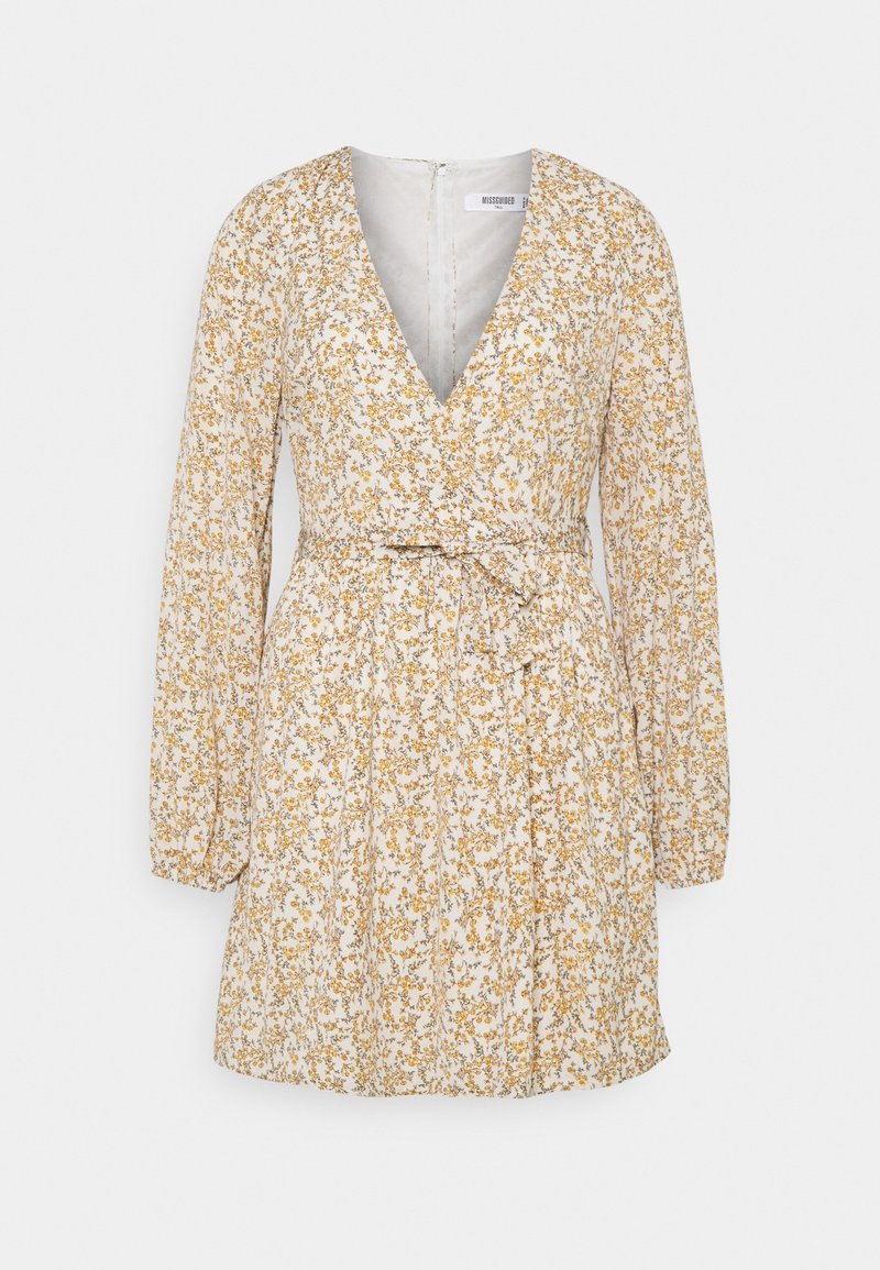 Robe mini blanche à manches longues avec petit imprimé floral jaune, encolure en V, taille cintrée et nœud à nouer à la taille à l'avant.