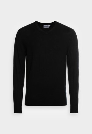 Schwarzer Langarm-V-Ausschnitt-Pullover mit Calvin Klein-Label im Kragen und dezentem Logo auf der Brust, vor weißem Hintergrund präsentiert.