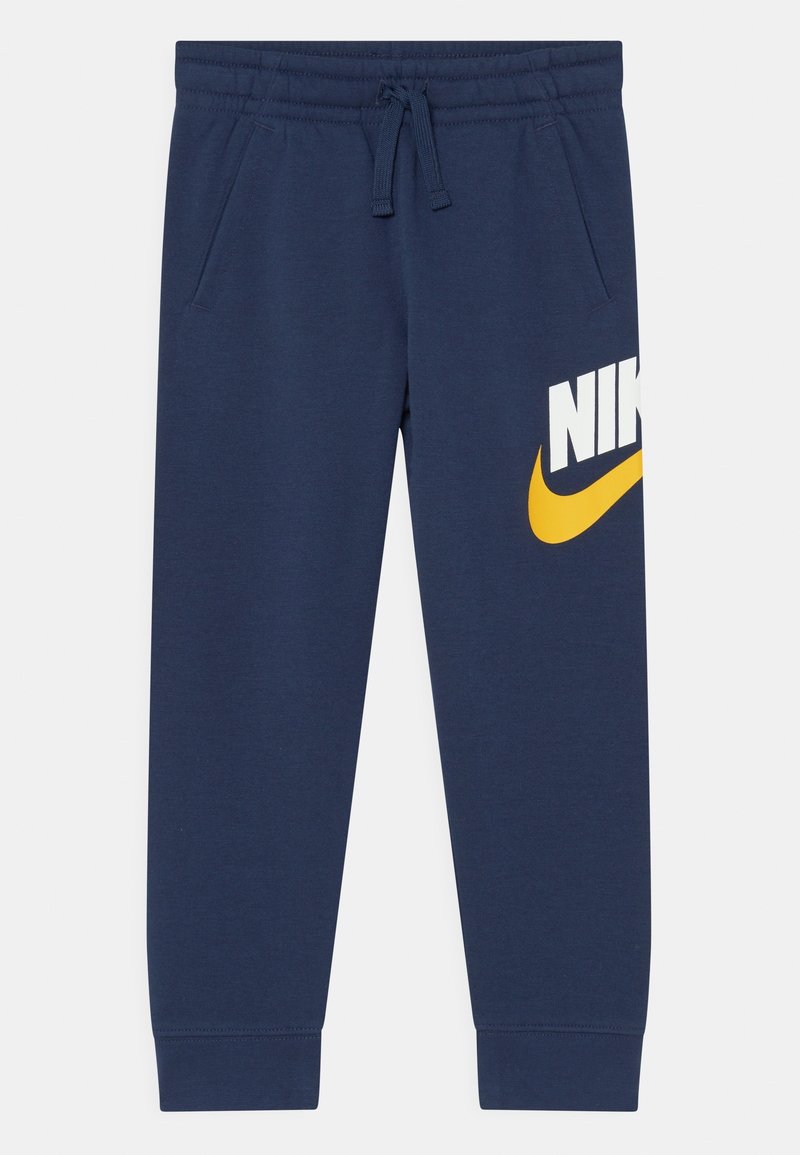 Navyblå joggers i mjukt tyg har ett elastiskt midjeband med dragsko. Framtstående gul och vit "NIKE"-logotyp på sidan.