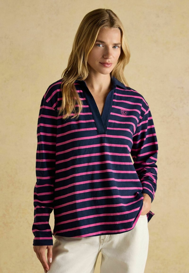 Tumepruun ja roosa triibuline pikkade varrukatega särk, millel on krae ja rinnal logo, valmistatud pehmest, tekstuurilisest kangast.