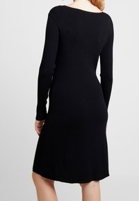 Czarna, żeberkowana sukienka z długim rękawem, dekoltem w łódkę i lekko rozszerzanym dołem, prezentująca teksturowany materiał oraz dopasowany krój.