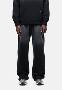 Zwarte katoenen hoodie met een voorzak, gecombineerd met losse, donkergrijze sweatpants met een gestructureerde afwerking en een trekkoord in de taille.