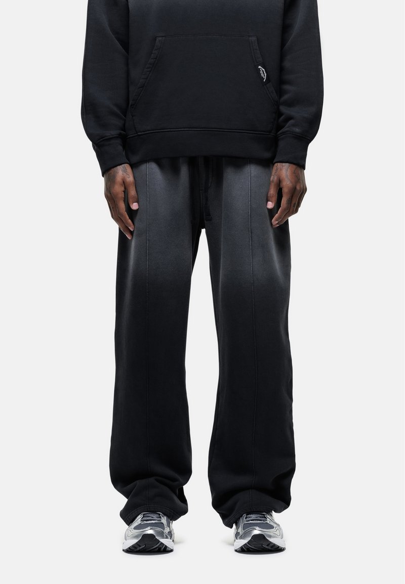 Zwarte katoenen hoodie met een voorzak, gecombineerd met losse, donkergrijze sweatpants met een gestructureerde afwerking en een trekkoord in de taille.