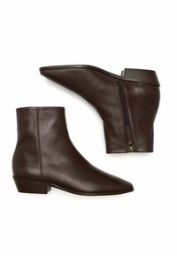 Botas de cuero marrón hasta el tobillo con punta afilada, pequeño tacón cuadrado y cremallera lateral para facilitar su uso. Textura suave, diseño minimalista.