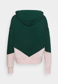 Sweat à capuche avec une partie supérieure vert foncé et une partie inférieure rose clair, présentant un design en chevron séparant les deux couleurs.