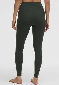 Sötétzöld, magas derekú leggings, sima, rugalmas anyagból készült. Illeszkedő fazon és minimalista varrási részletek találhatók a hátulján.