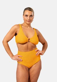 Gult bikini-set som har en texturerad, ribbad tyg. Toppen har en djup V-halsringning och en cirkulär accent i mitten. Höga midjebyxor.