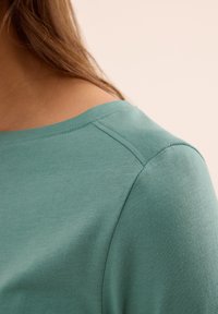 Lichtgroen katoenen top met een ronde halslijn en een gladde textuur, met zichtbare schoudernaden en een ontspannen pasvorm.