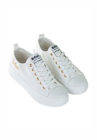 Białe trampki z płótna z złotymi oczkami, teksturowaną gumową podeszwą i metką z logo na języku. Posiadają przeszycia i pętelkę na pięcie.