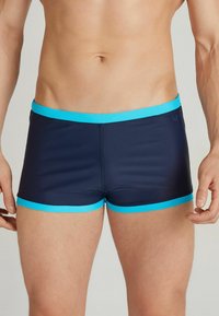 Marineblaue Badeshorts mit einem elastischen türkisfarbenen Bund und Saum. Das Material scheint glatt und körpernah zu sein, mit einem stromlinienförmigen Design.