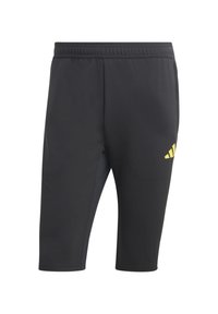 Zwarte sportieve shorts van gladde stof met een taps toelopend ontwerp. Een opvallend geel Adidas-logo is geplaatst op de linker bovenbeen.