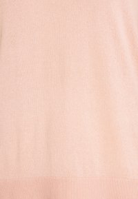 Světle růžový svetr s jemnou pletenou texturou. Hladký lem na spodní části, bez švů, bez viditelných zapínání nebo ozdob.