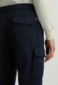 Marine cargo pants met meerdere zakken, voorzien van een klepzak op de achterkant en een klein logo accent bij de tailleband. Glad stoftextuur.