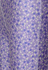 Fialová látka s květinovým vzorem s malými zelenými a modrými květy, doplněná bílým šitím podél švu.