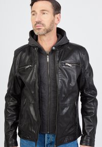 Sort læderjakke med lynlåslommer og en aftagelig grå hættetrøje under. Glat tekstur og tætsiddende design.