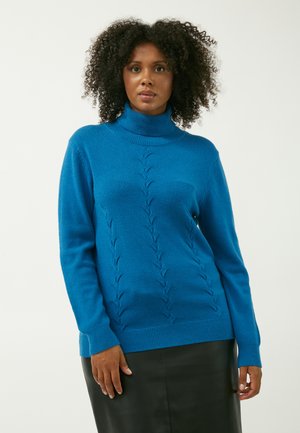 Maglione a dolcevita color teal con design a treccia, polsini e orlo a coste, realizzato in un morbido tessuto, abbinato a una gonna in pelle nera.