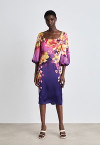 Satin Kleid mit einem floralen Muster in lebhaften Farben. Verfügt über Puffärmel, einen quadratischen Ausschnitt und eine figurbetonte Silhouette.