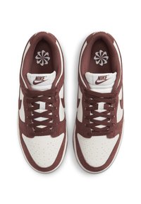 Sneakers Nike con tomaia in pelle bianca, dettagli in camoscio bordeaux, lacci rotondi, punta traforata e logo sulla linguetta.