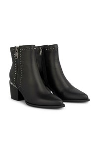 Botas de tobillo de cuero negro con punta afilada, cremalleras laterales y adornos de tachuelas plateadas a lo largo de la costura exterior. Diseño de tacón cuadrado.