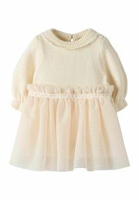 Strikket kremfarget topp med puffeermede ermer, pyntet med et mykt kremfarget tyllskjørt med volangkant på midjen og knappelukking bak.