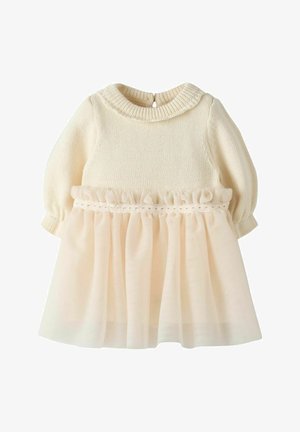 Pleteni kremasti top s napuhanih rukavima, ukrašen mekanom kremastom suknjom od tila, s volanastim pojasom i zatvaranjem na gumbe na leđima.