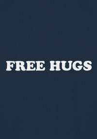 T-shirt en coton bleu marine avec un texte brodé en blanc qui dit "FREE HUGS" dans un style de police rétro et épaisse.