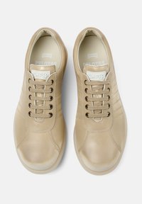Zapatillas de piel beige con punta redonda, cordones planos y parche con logo. Presenta detalles de costura y plantilla acolchada para mayor comodidad.