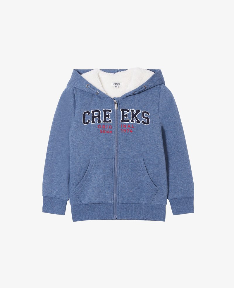 Sudadera azul con cremallera hecha de un tejido suave y texturizado, con forro de felpa blanca. Presenta "CREEKS ORIGINAL Desde 1974" en colores contrastantes y dos bolsillos frontales.