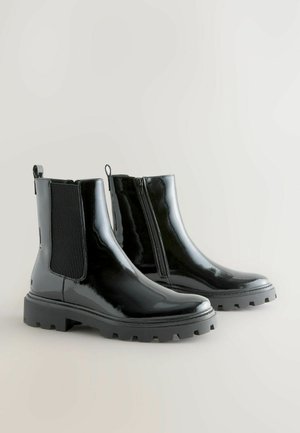Černé lakované kotníkové boty s elastickými postranními panely, zadním poutkem a robustní gumovou podrážkou. Obsahuje zip na boku pro snadné obouvání.