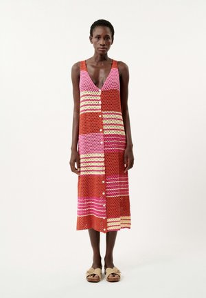 Une robe sans manches en tricot avec des rayures rouges, roses et jaunes, avec une fermeture à boutons sur le devant et une longueur arrivant mi-mollet.