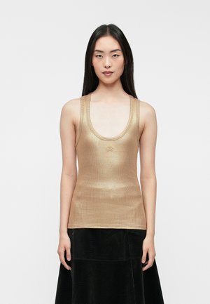 Metallisk guld tanktop med rund halsudskæring og brede stropper, der har en tætsiddende silhuet. Sammen med en sort struktureret nederdel.