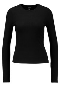 Svart långärmad topp med ribbad textur, rund halsringning, figurnära design och minimal sömnad. Lämplig för avslappnad lager-på-lager-stil.