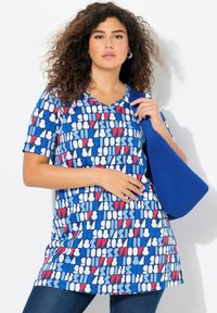 Tunique bleue texturée avec un motif géométrique en rouge, blanc et bleu. Design en V, manches courtes, et accompagnée d'un sac bleu.