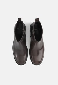 Brown leather ankle boots with a sleek design, rounded toe, and zipper detail on the side. Smooth texture and minimalistic look.