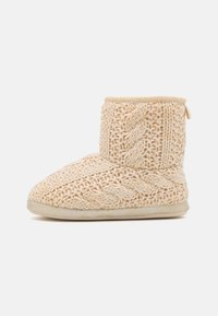 Gehaakte sloffen in een beige kleur met een gestructureerd gevlochten patroon, enkelhoogte en een zachte zool voor comfort. Voorzien van een trekband aan de achterkant.