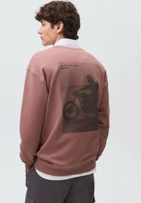 Felpa marrone con vestibilità comoda, caratterizzata da una grande grafica di una motocicletta sul retro e dalla scritta "NESSUNA DESTINAZIONE NECESSARIA."