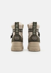 Buffalo støvler med en beige tekstureret overdel og olivengrønne detaljer, robust hæl, brandingelementer og en slidstærk sål.