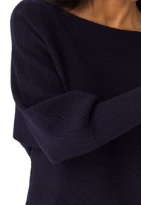 Maglione a coste in blu navy con scollatura ampia e maniche lunghe, caratterizzato da un tessuto testurizzato con sottili linee orizzontali.